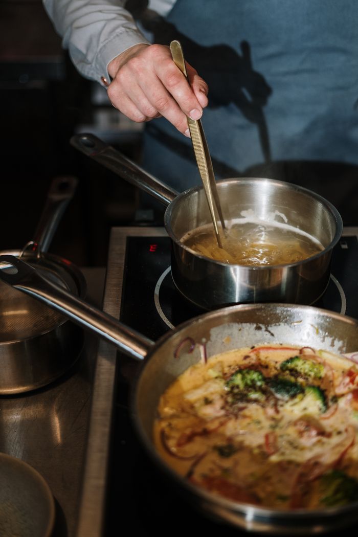 A chef cooks a gourmet meal using stainless steel cookware on a modern stovetop.